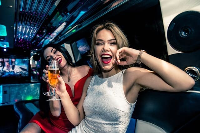ladies in white and red night dress having champagne and party at the back of a stretch limousine hire in Melbourne